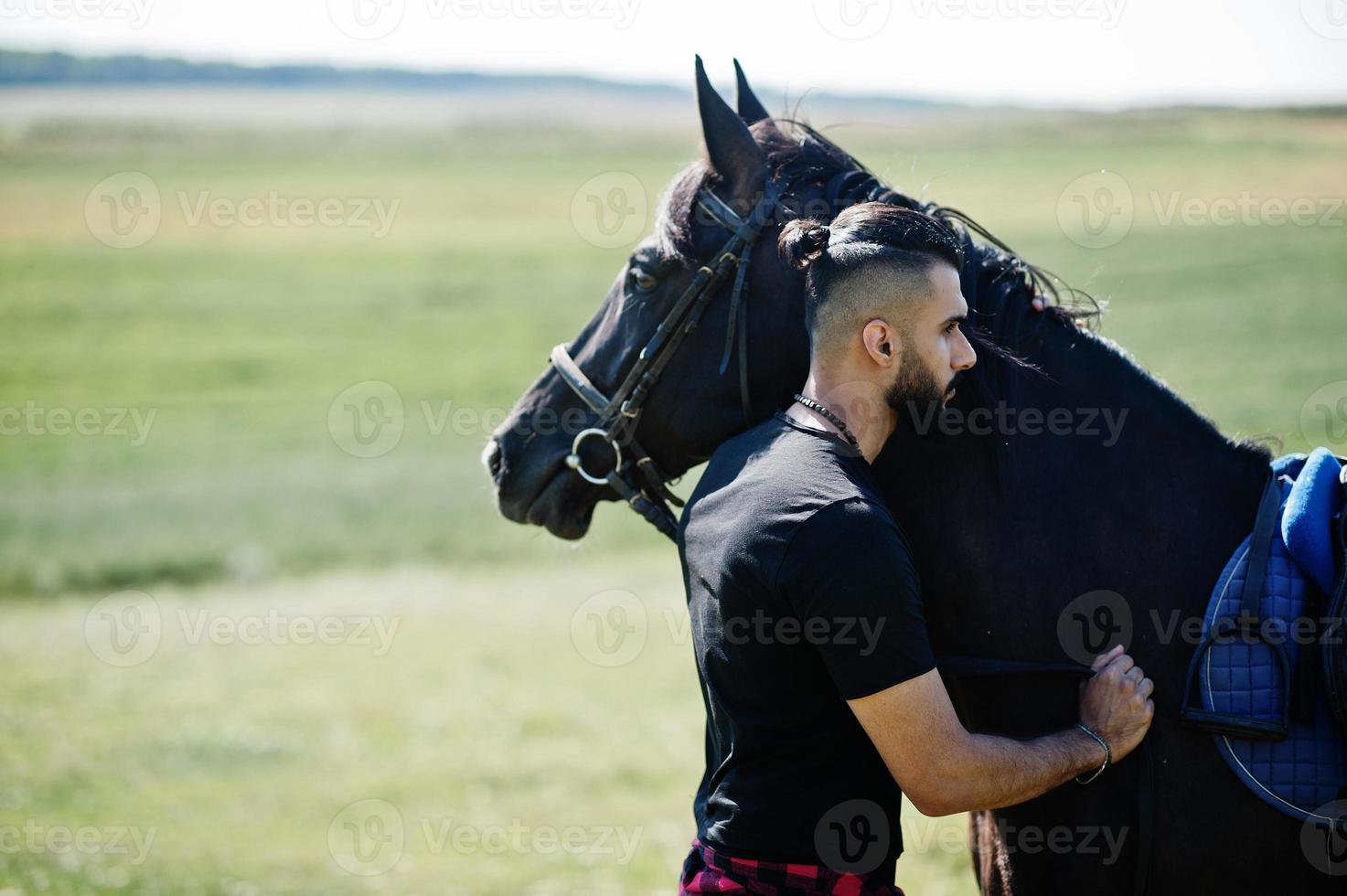 Arab tall beard man wear in black with arabian horse. photo