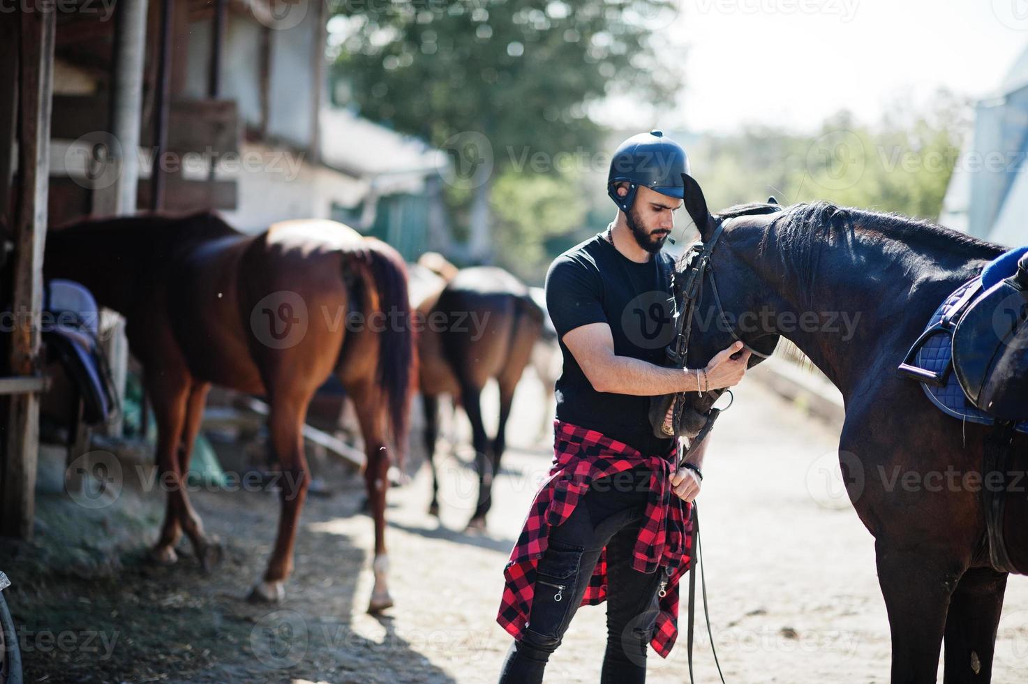 Arab tall beard man wear in black helmet with arabian horse. photo