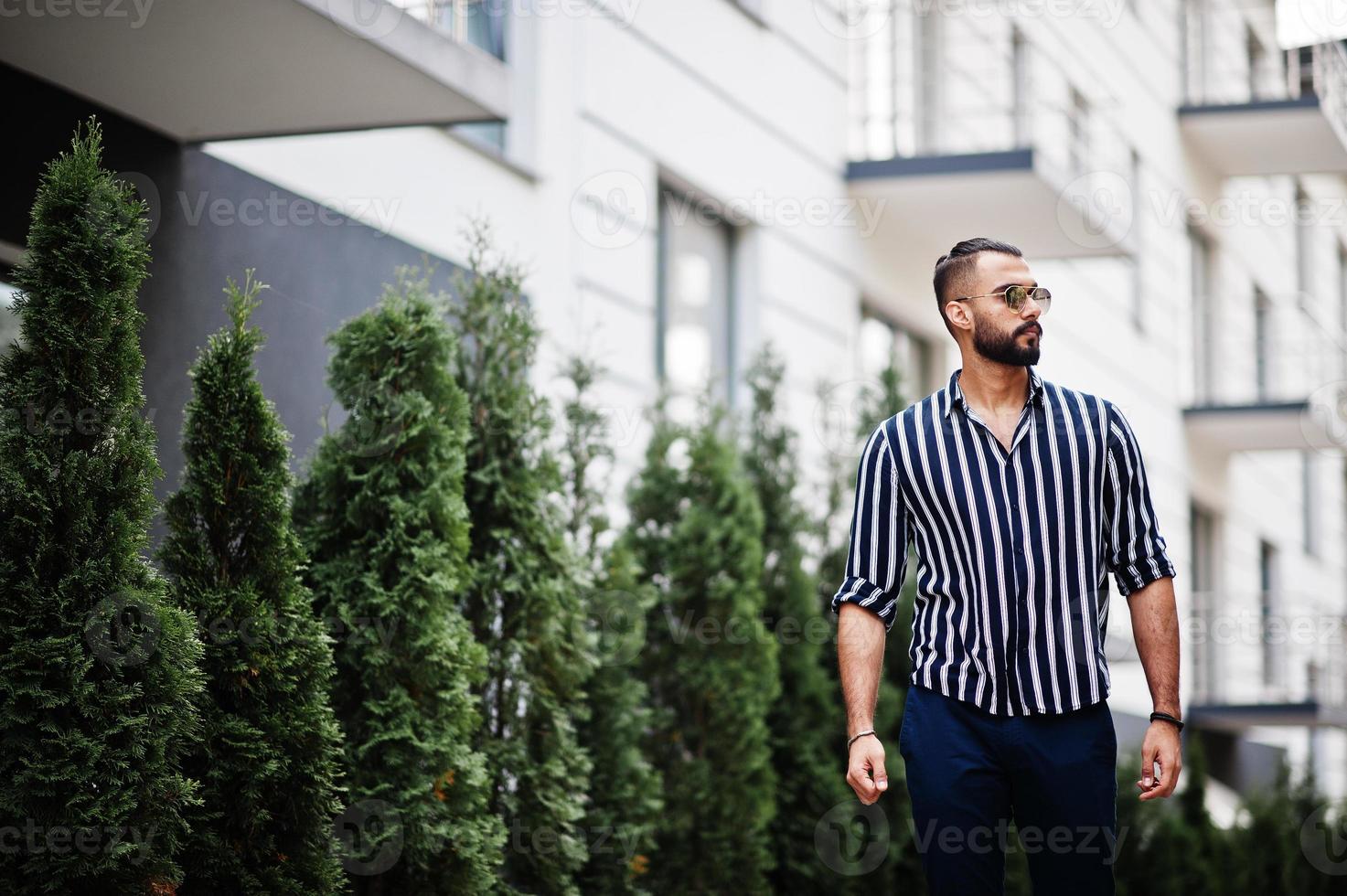 Successful arab man wear in striped shirt and sunglasses pose outdoor. photo