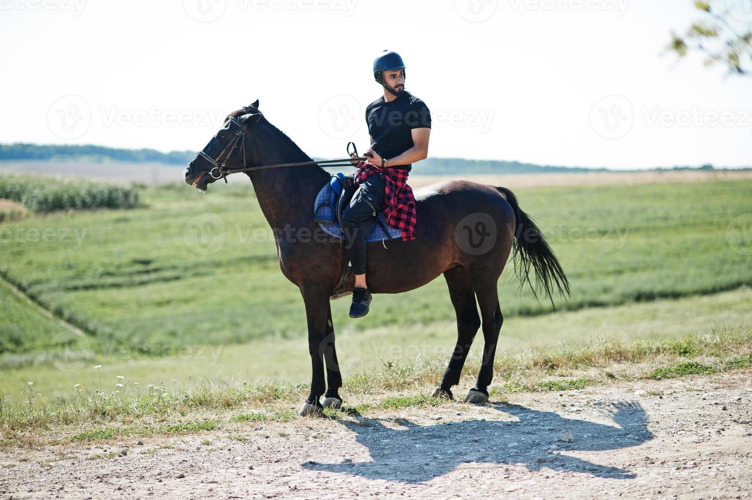 Arab tall beard man wear in black helmet, ride arabian horse. photo