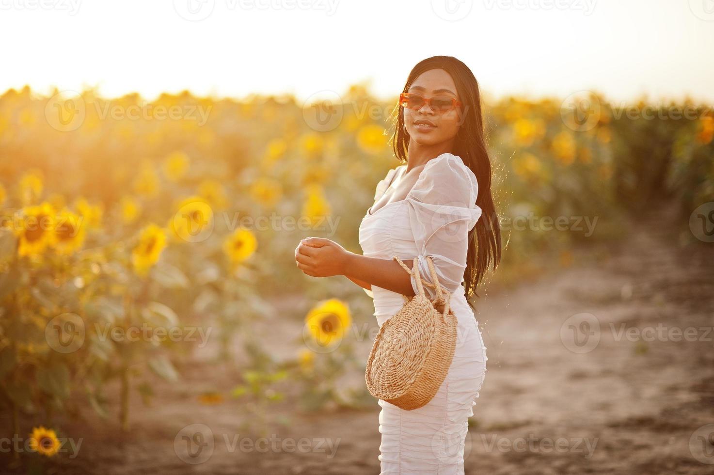 Pretty young black woman wear summer dress pose in a sunflower field. photo