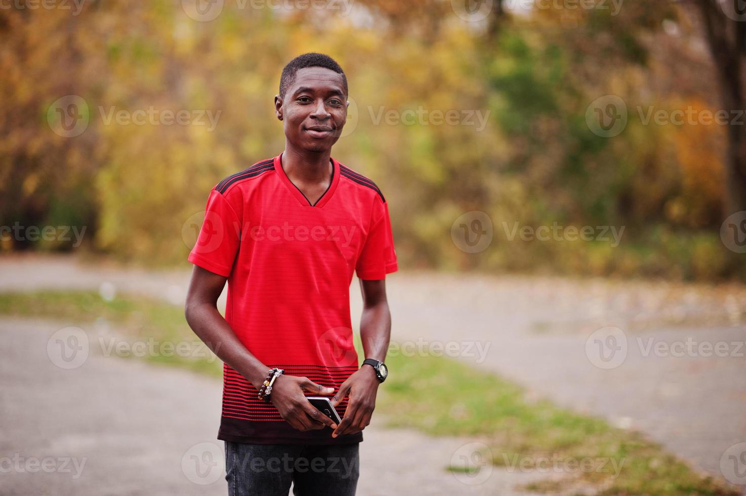 hombre afroamericano en camiseta deportiva de fútbol roja contra el parque de otoño. foto