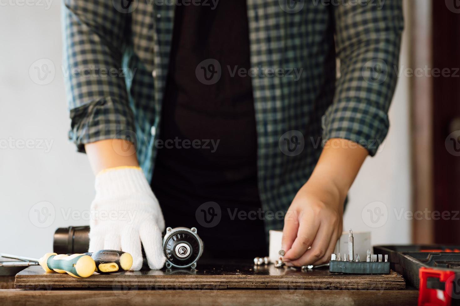 Close up of male mechanic holding electric cordless screwdriver drill with wood screw in the factory. Working with the screw. Professional carpenter. Concept furniture at home. photo