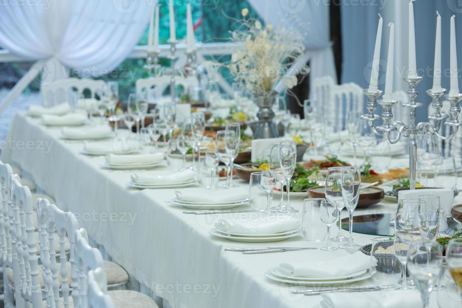 Empty banquet hall ready to receive guests on the summer terrace. white festive table photo