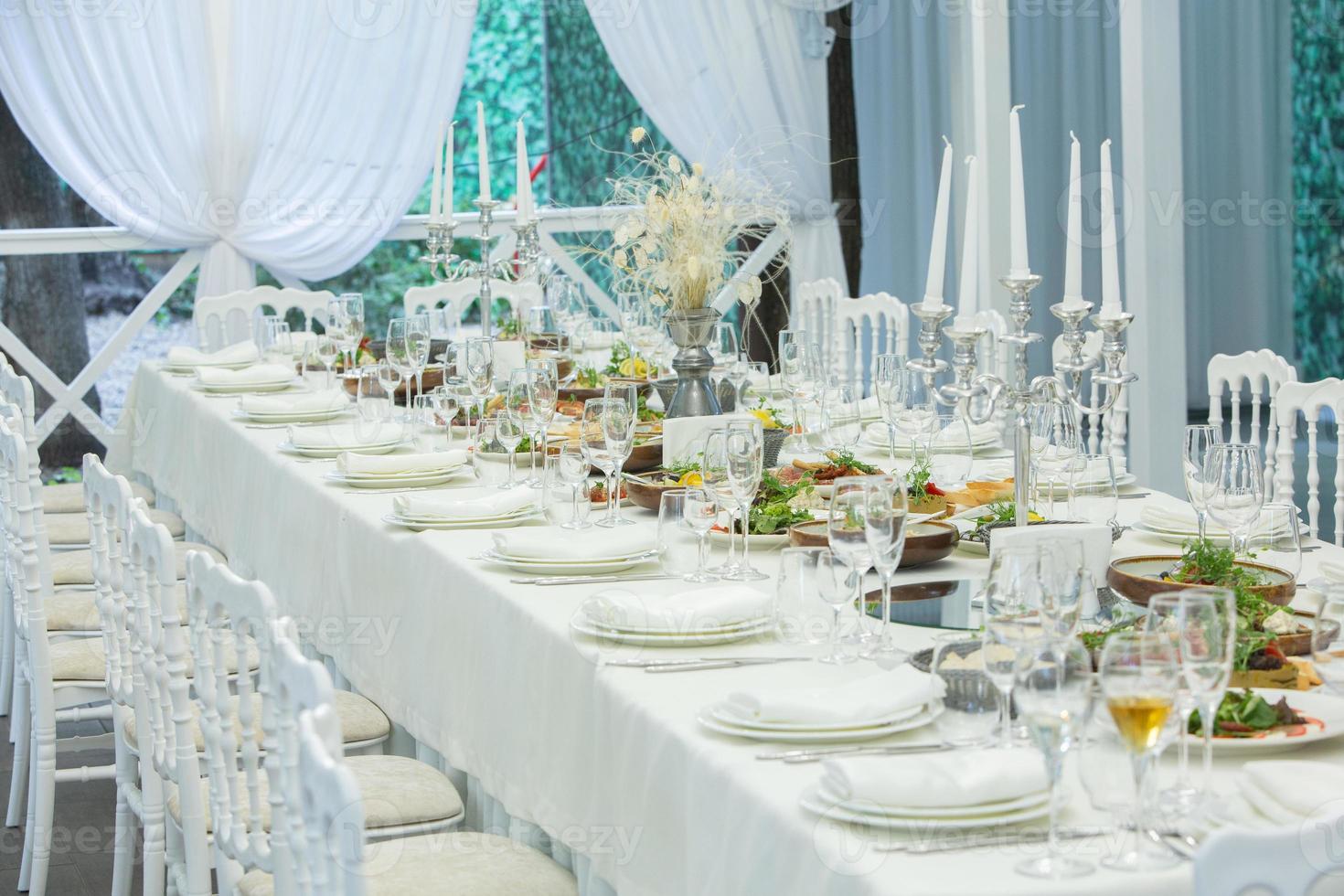 Empty banquet hall ready to receive guests on the summer terrace. white festive table photo