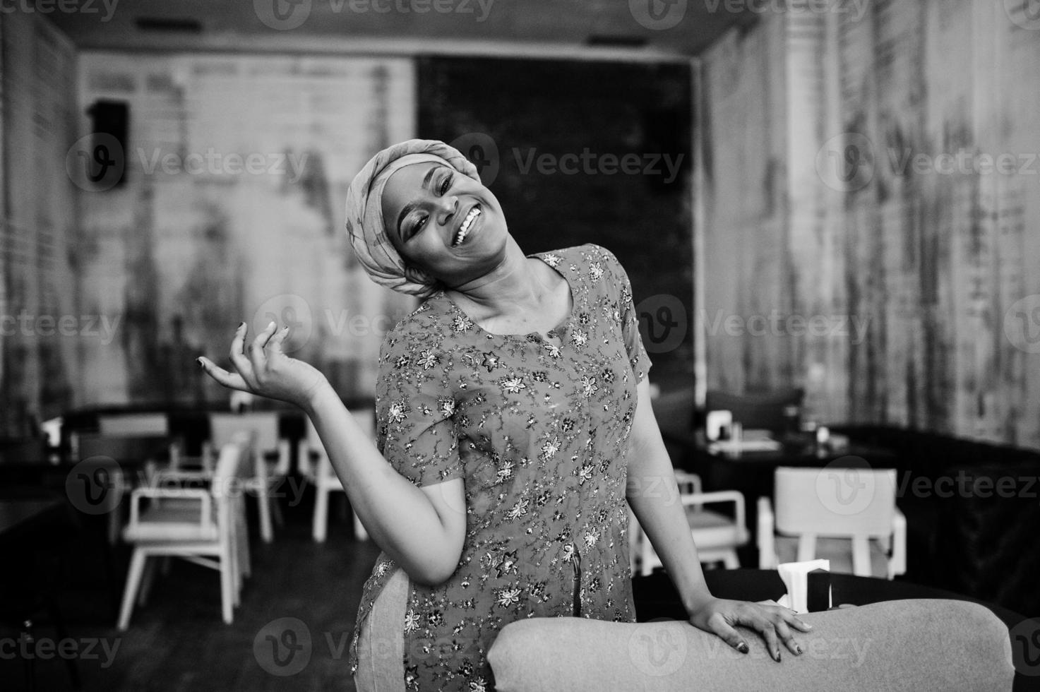 elegante mujer africana con camisa roja y sombrero posó en un café interior. foto