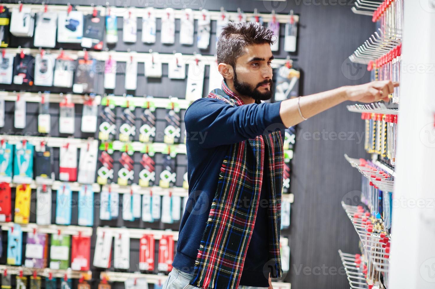 el comprador de un cliente indio en una tienda de teléfonos móviles elige un estuche para su teléfono inteligente. concepto de pueblos y tecnologías del sur de Asia. tienda de celulares foto