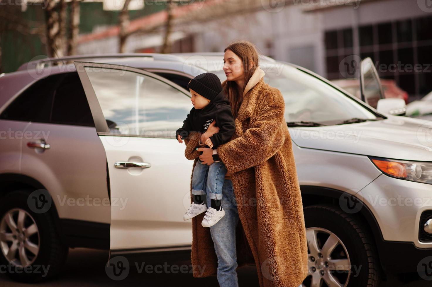 Young mother and child stand near they suv car. Safety driving concept. photo