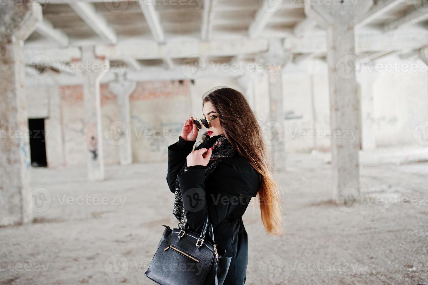 Brunette stylish casual girl in scarf and handbag against abandoned factory place. photo