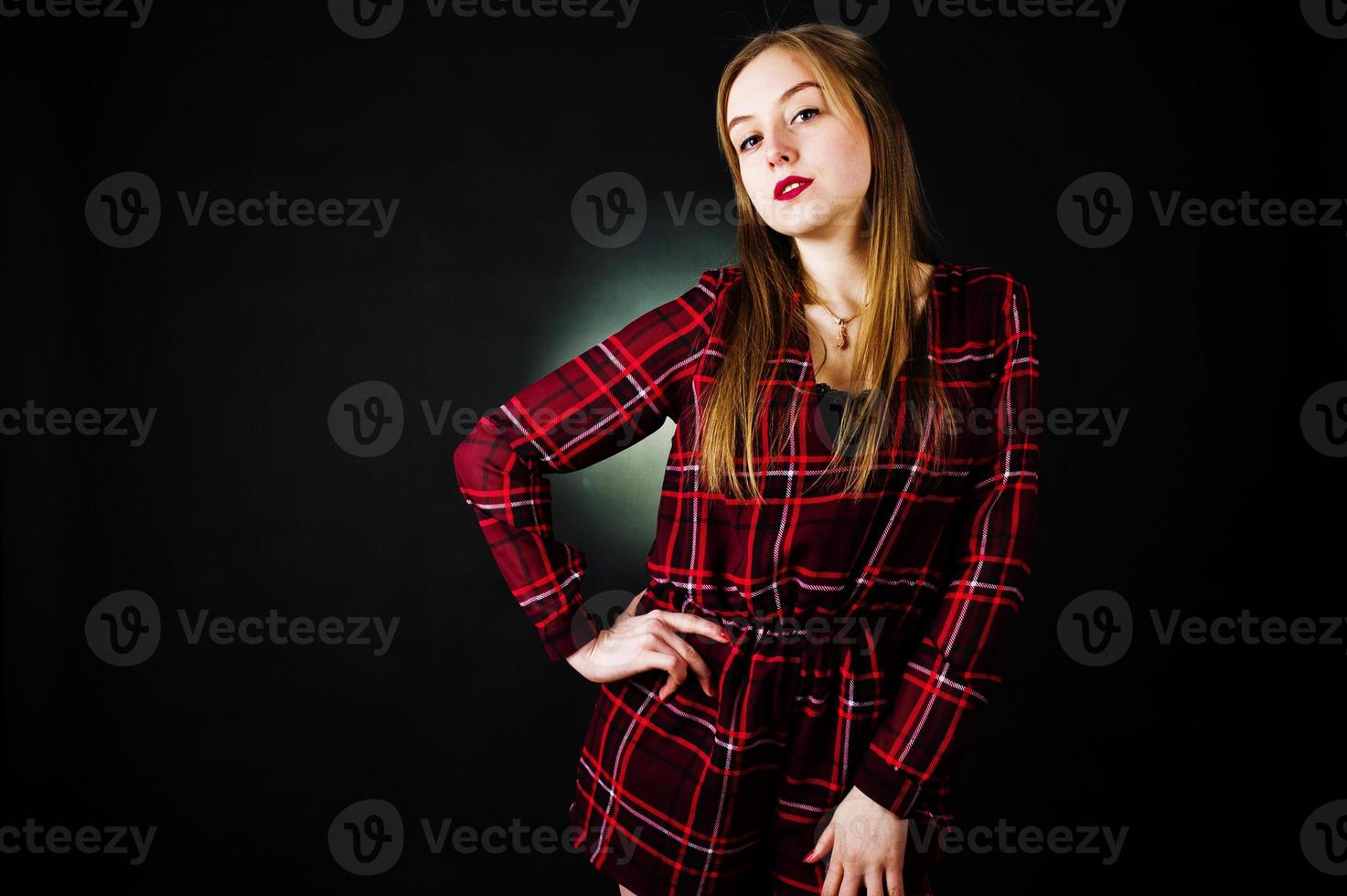 Young blonde girl in checkered dress at black background. photo
