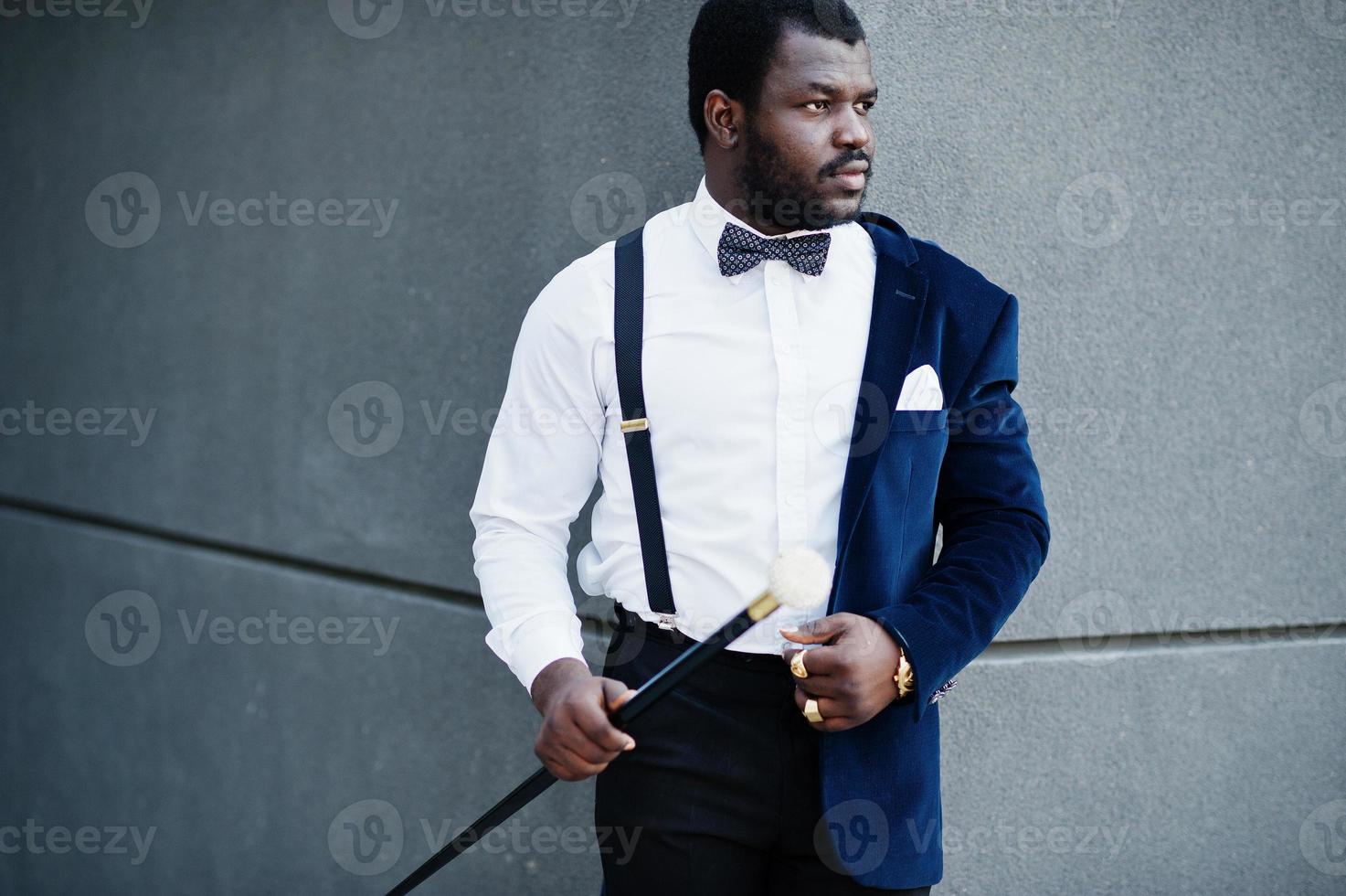 Handsome fashionable african american man in formal wear and bow tie with walking stick. photo