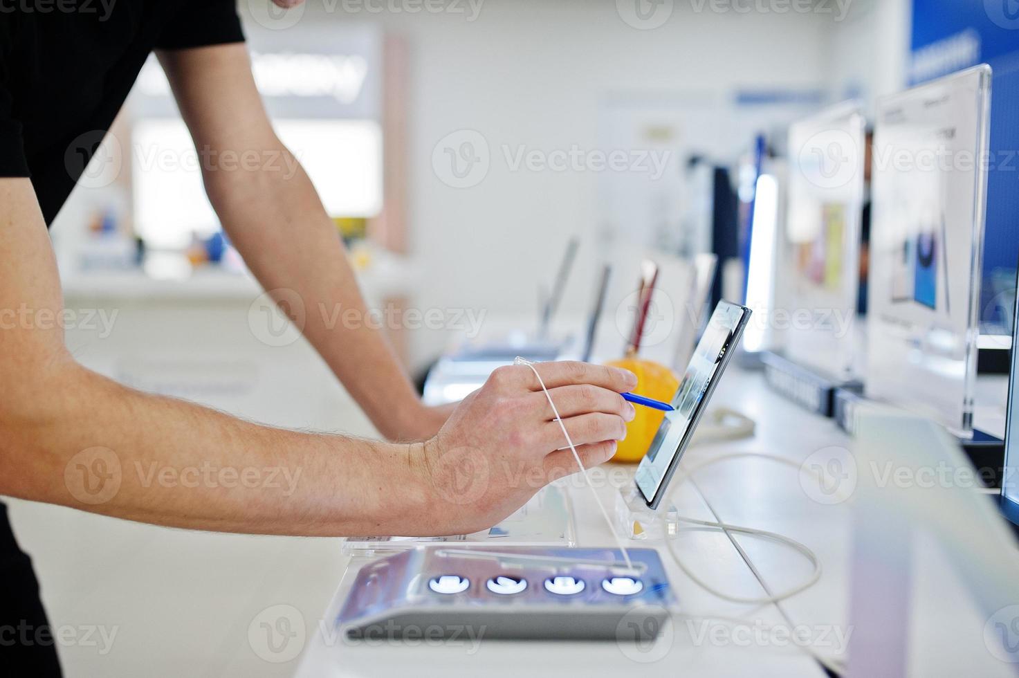 Seller man mobile phone professional consultant in tech store or shop hold new smartphone at hand and use stylus. photo