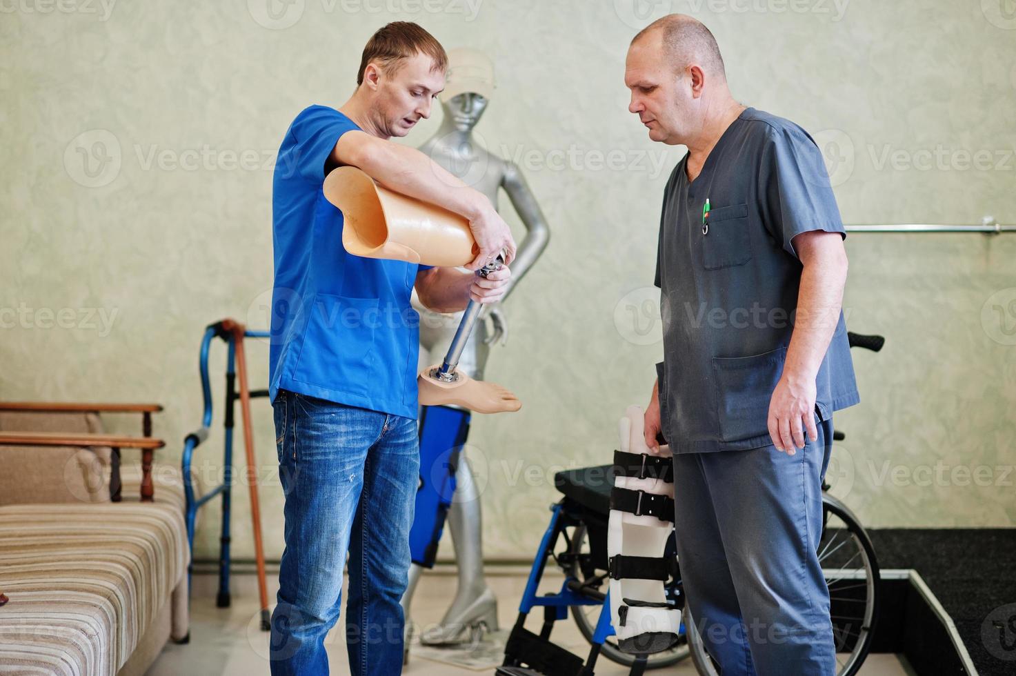 Two prosthetist man workers with prosthetic leg working in laboratory. photo