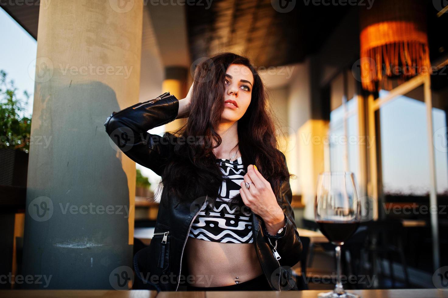 Young curly woman enjoying  her wine in a bar. photo