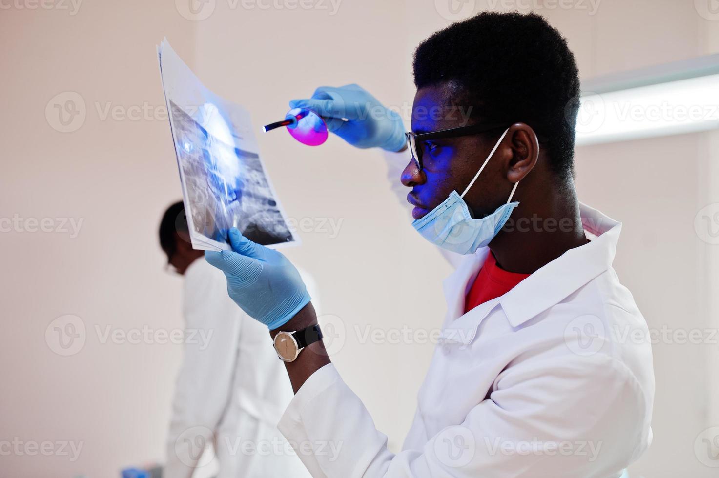 Dentist office and doctor practice concept. Close uo of hands professional african american doctor at dentistry medical pointing on teeth X-ray. photo