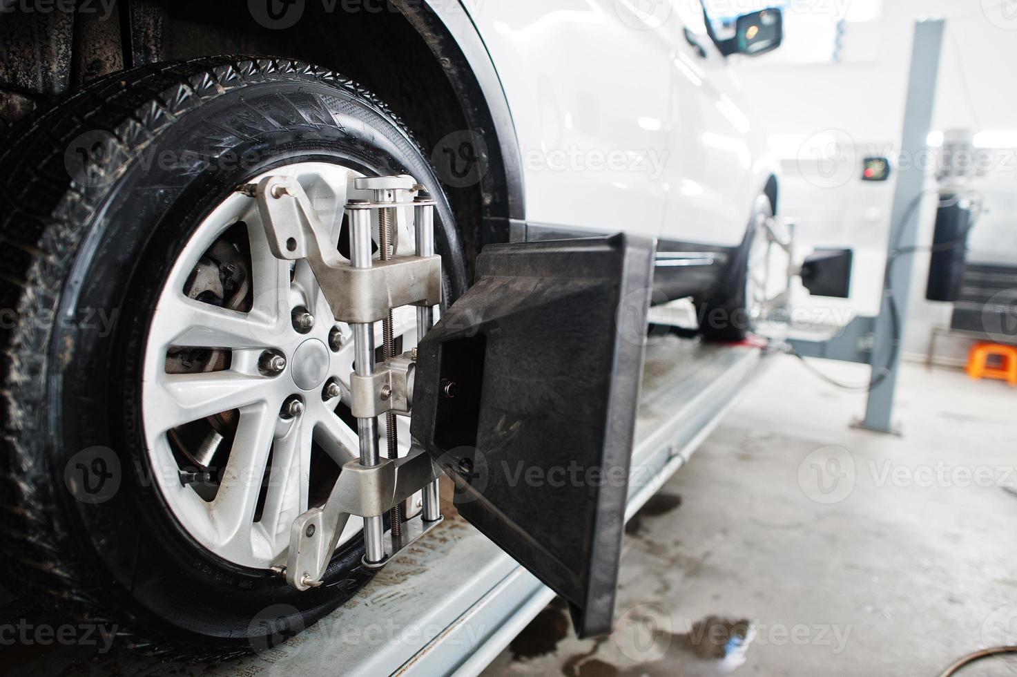 American SUV car on stand for wheels alignment camber check in workshop of service station. photo
