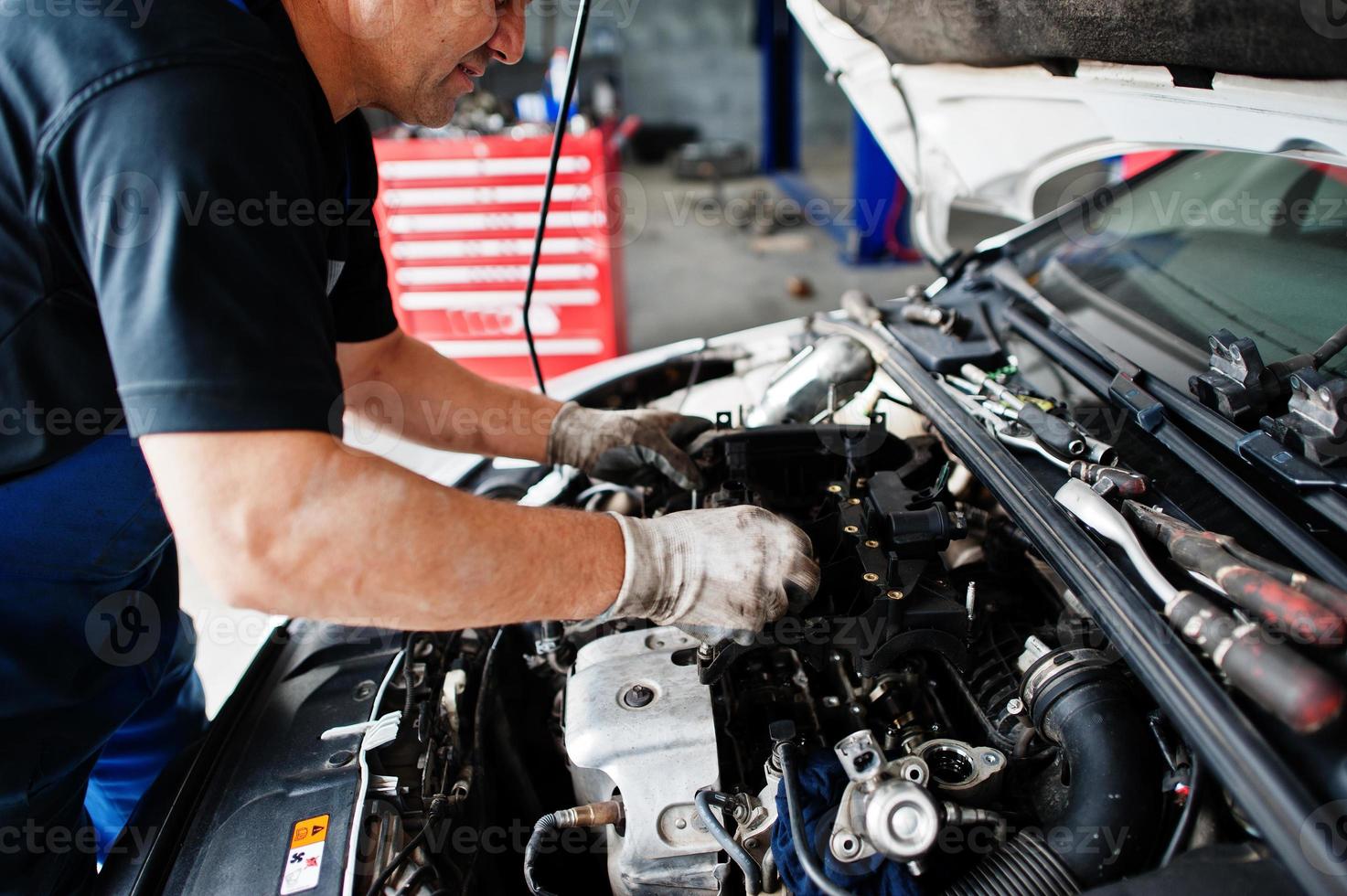 Car repair and maintenance theme. Mechanic in uniform working in auto service, checking engine
