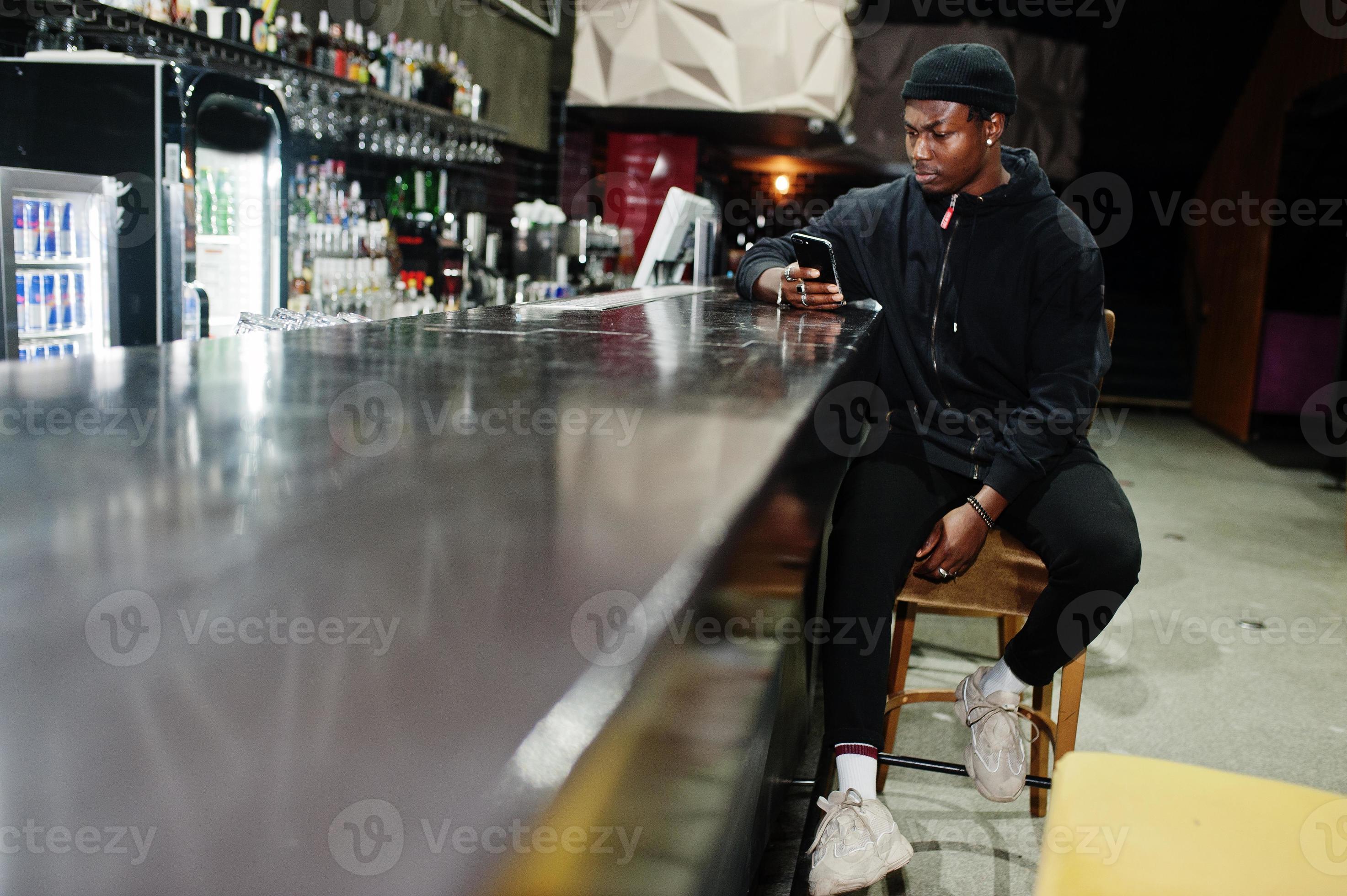 Handsome african american man posing inside night club in black hat
