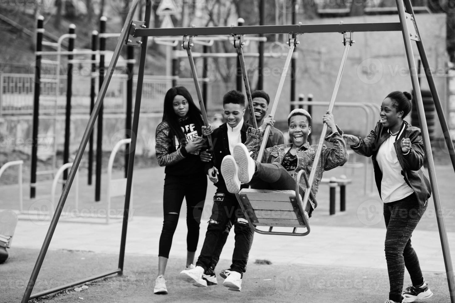 Young millennials african friends on playground, slide and swing. Happy black people having fun together. Generation Z friendship concept. photo