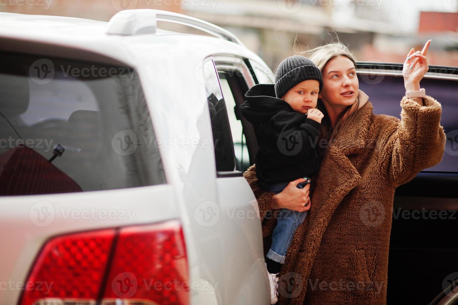 Young mother and child stand near they suv car. Safety driving concept. photo