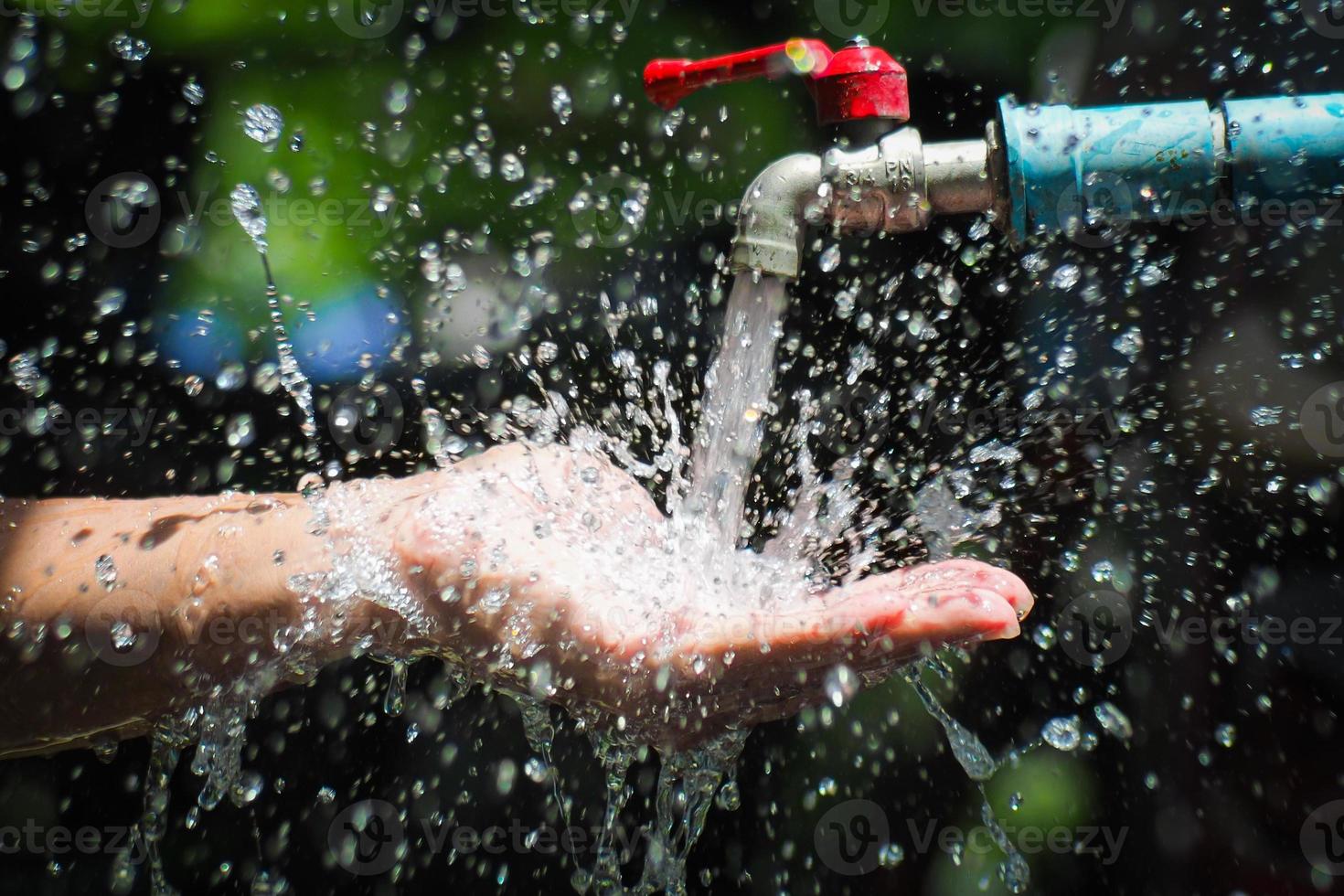 concepto de agua en la vida cotidiana. manos sosteniendo el agua que fluye del grifo. agua salpicando del grifo foto