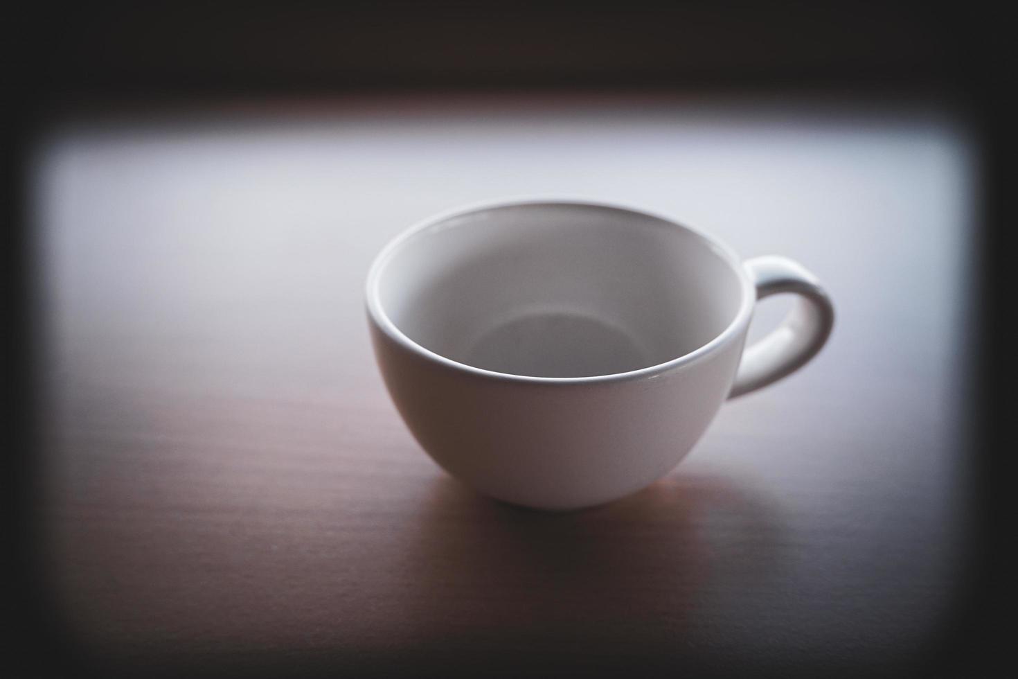 una vieja taza de té blanca se colocó sobre la mesa por la mañana con luz y sombra. foto