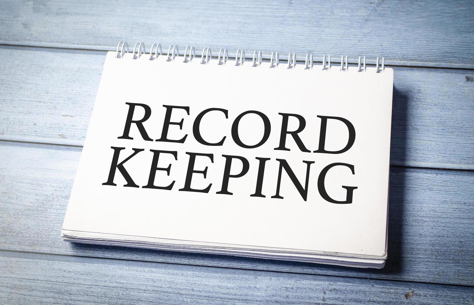 RECORD KEEPING word on notepad and blue wooden background photo