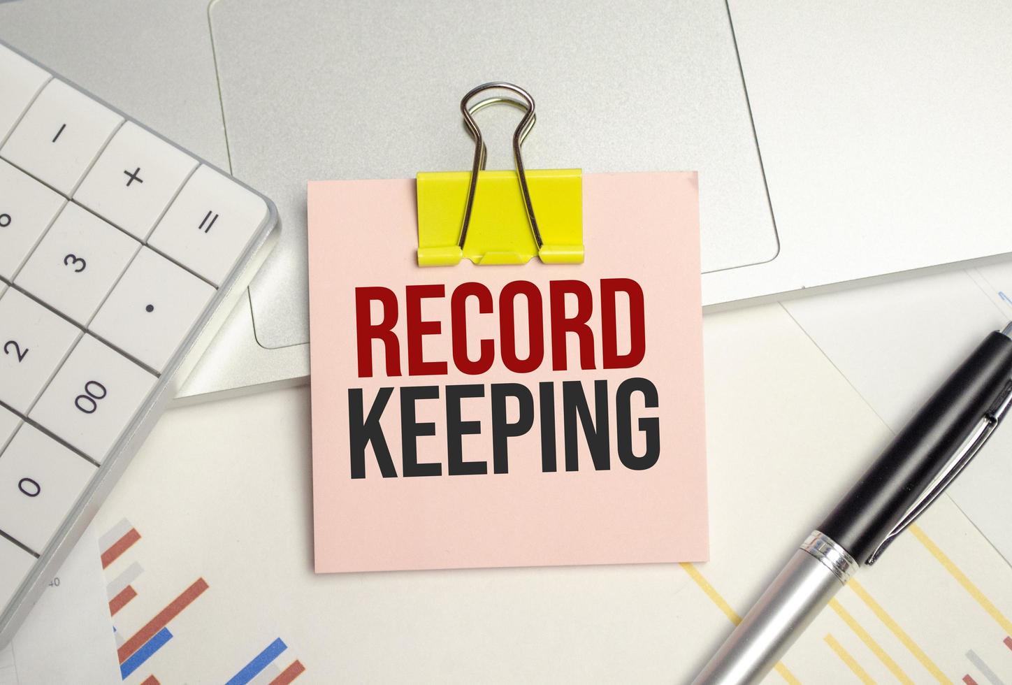 RECORD KEEPING symbol. pink paper sheet and pen, calculator and charts photo