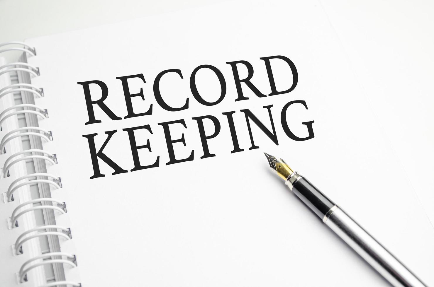 RECORD KEEPING words on white notepad and pen photo