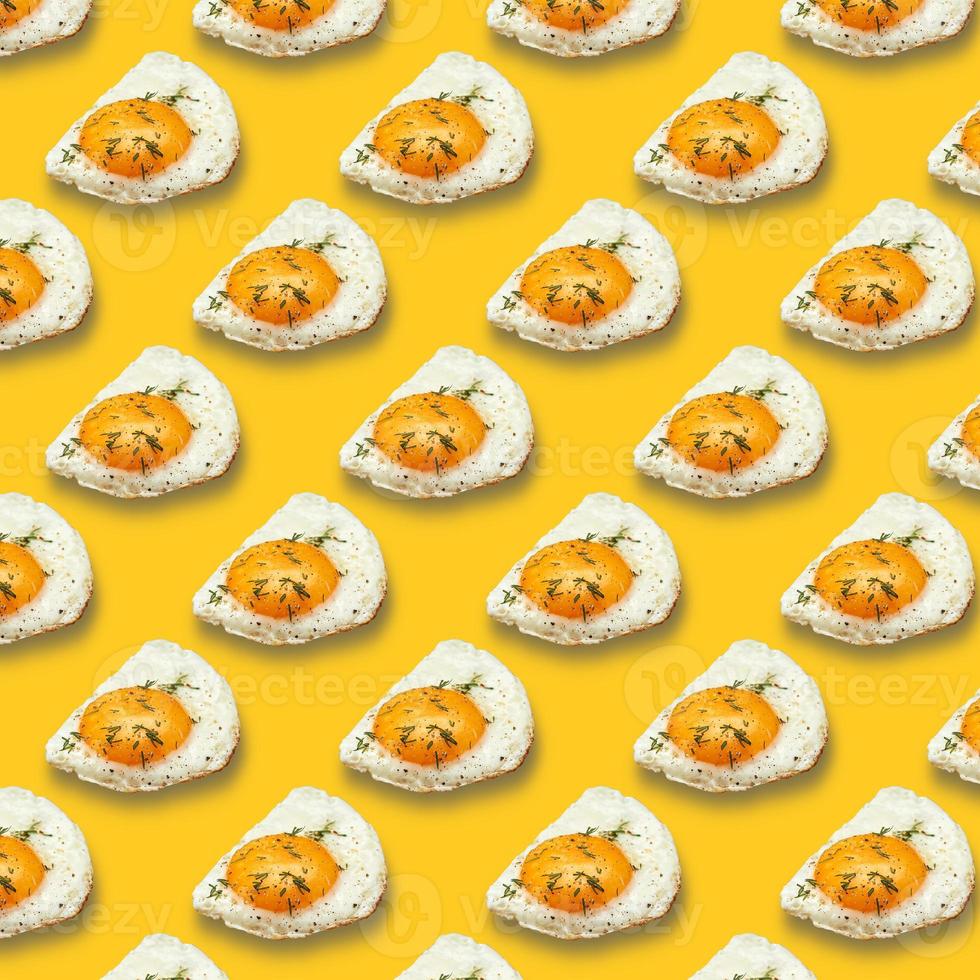 Chicken fried egg sprinkled with herbs isolated on yellow background. Scrambled eggs close-up seamless pattern. photo