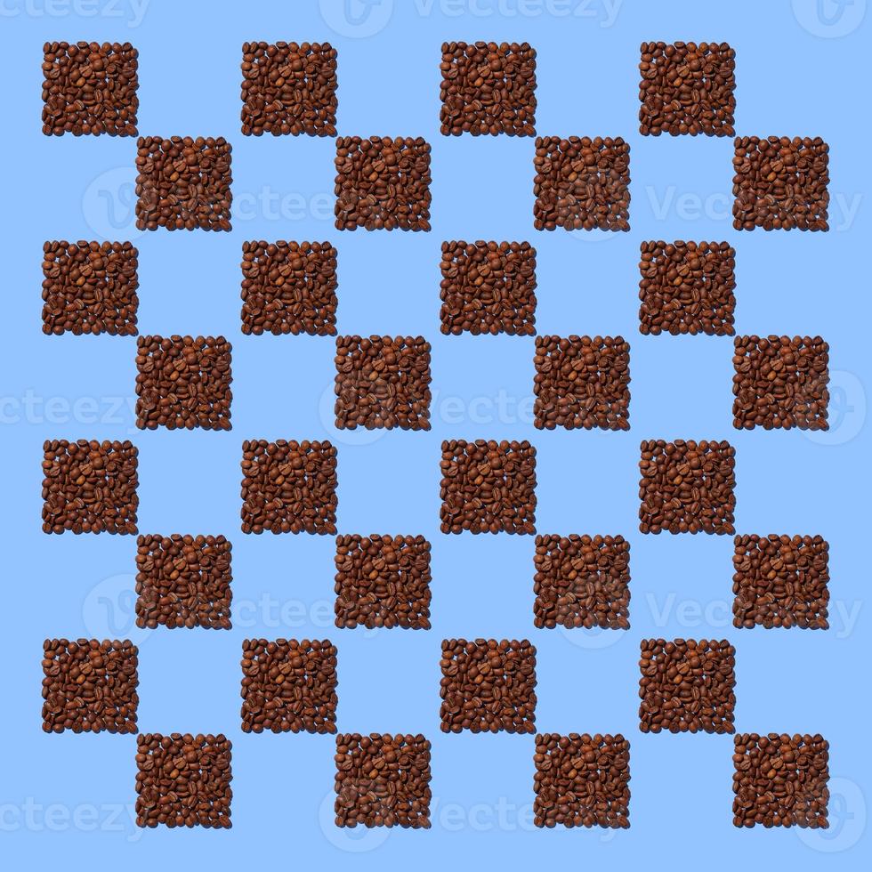 Squares from coffee grains on blue background. A pattern in the form of a chessboard of coffee beans poured in the form of squares. photo