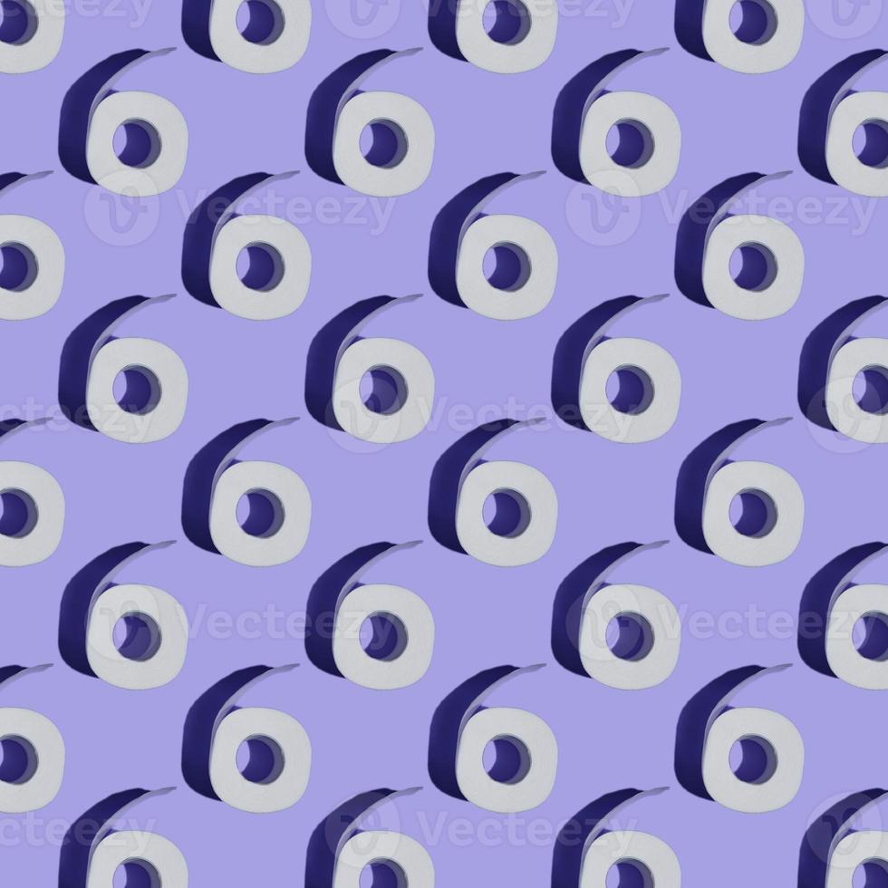 Seamless Pattern made of Toilet paper rolls close-up isolated on purple background. Top view. The concept of hygiene. photo