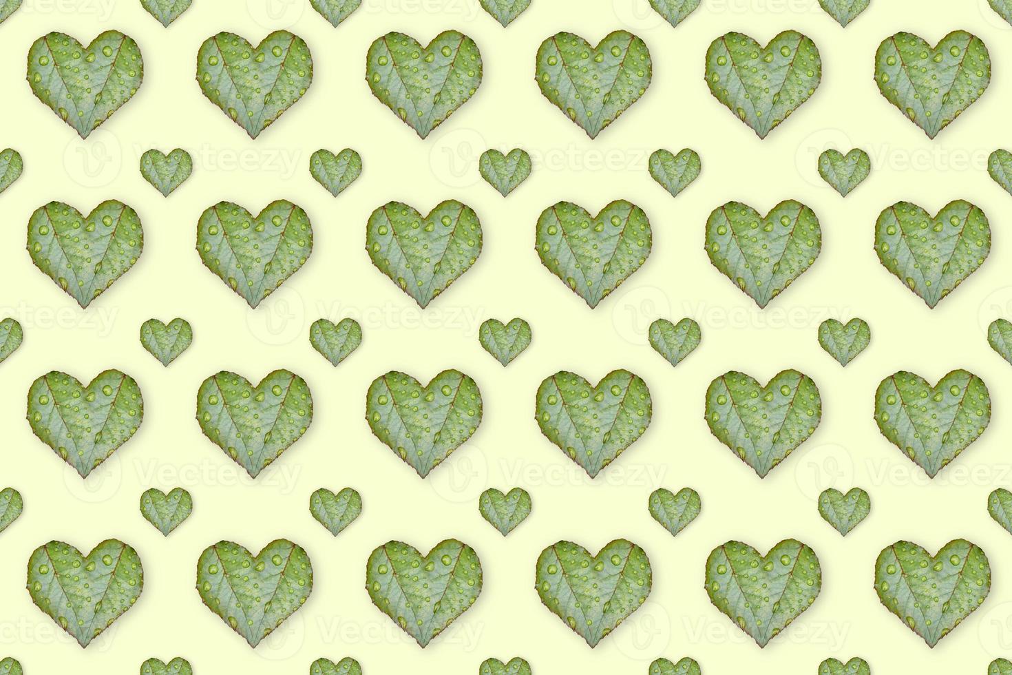 Green leaves in the shape of heart seamless pattern on light yellow background. The concept of love. photo