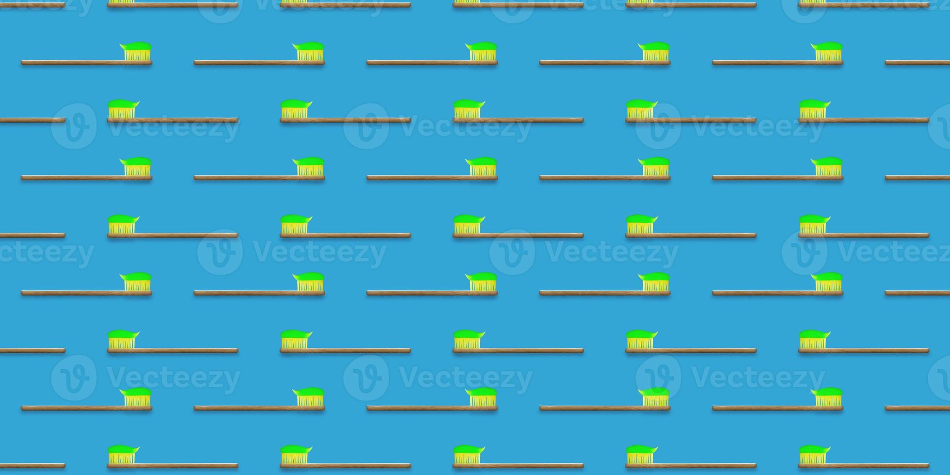 Seamless pattern of wooden tooth brushes isolated on blue background. Green toothpaste on toothbrush. photo
