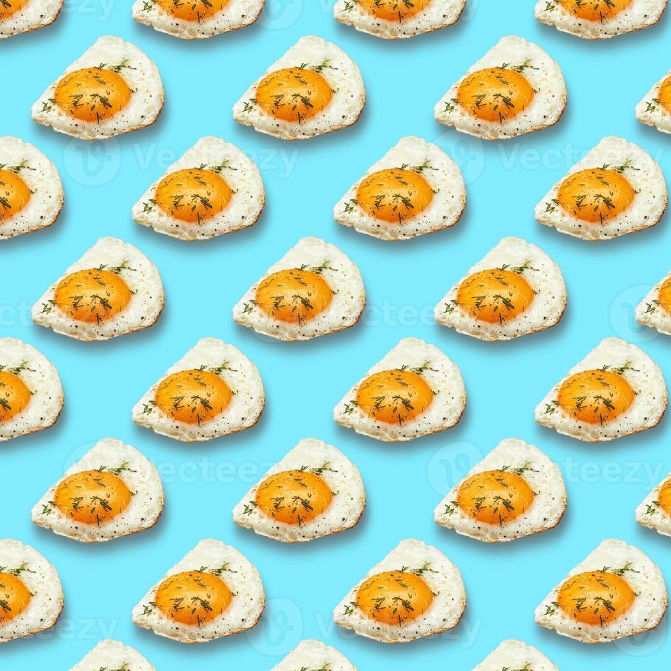 Chicken fried egg sprinkled with herbs isolated on blue background. Scrambled eggs close-up seamless pattern. photo