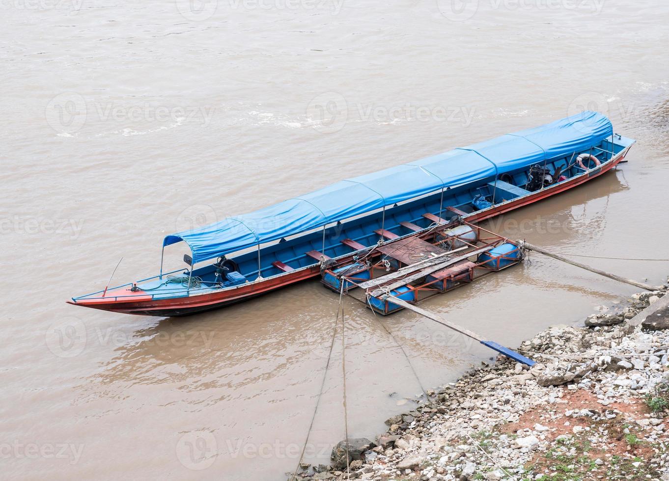 el bote de cola larga está flotando cerca del pontón local. foto