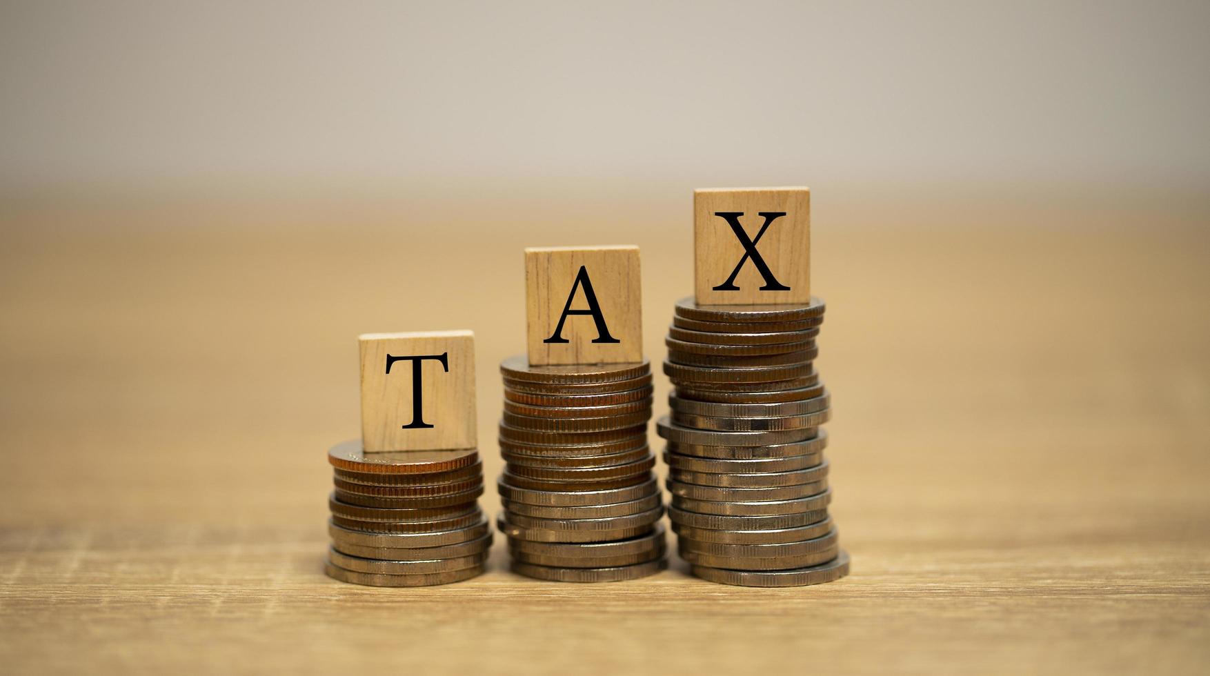 bloques de madera con la palabra impuesto sobre monedas apiladas. concepto de impuesto sobre la renta. foto