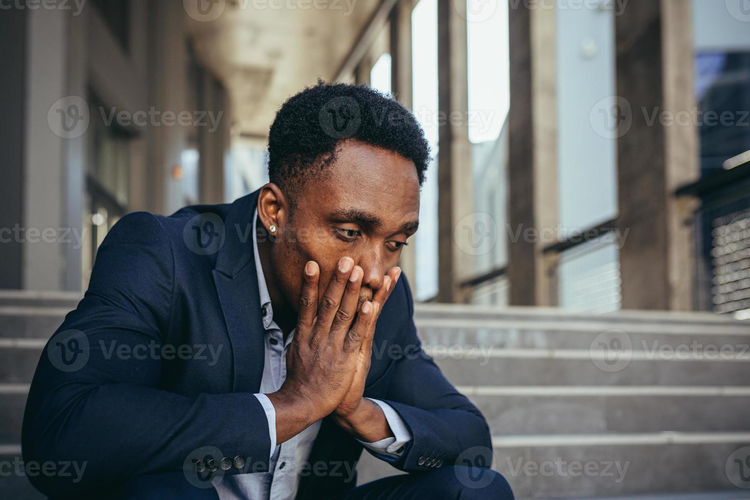 trabajador de oficina masculino cansado después del trabajo, afroamericano tiene dolor de cabeza severo, sentado foto