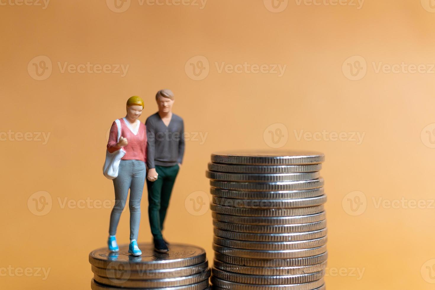 gente en miniatura, pareja feliz de pie en la pila de monedas foto