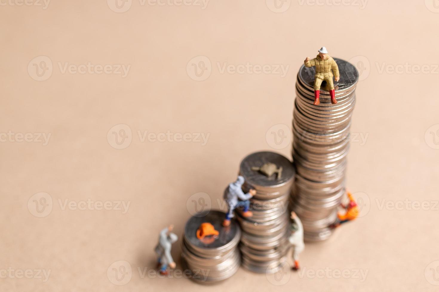 Miniature people Mountain climber ascending the coin stack photo