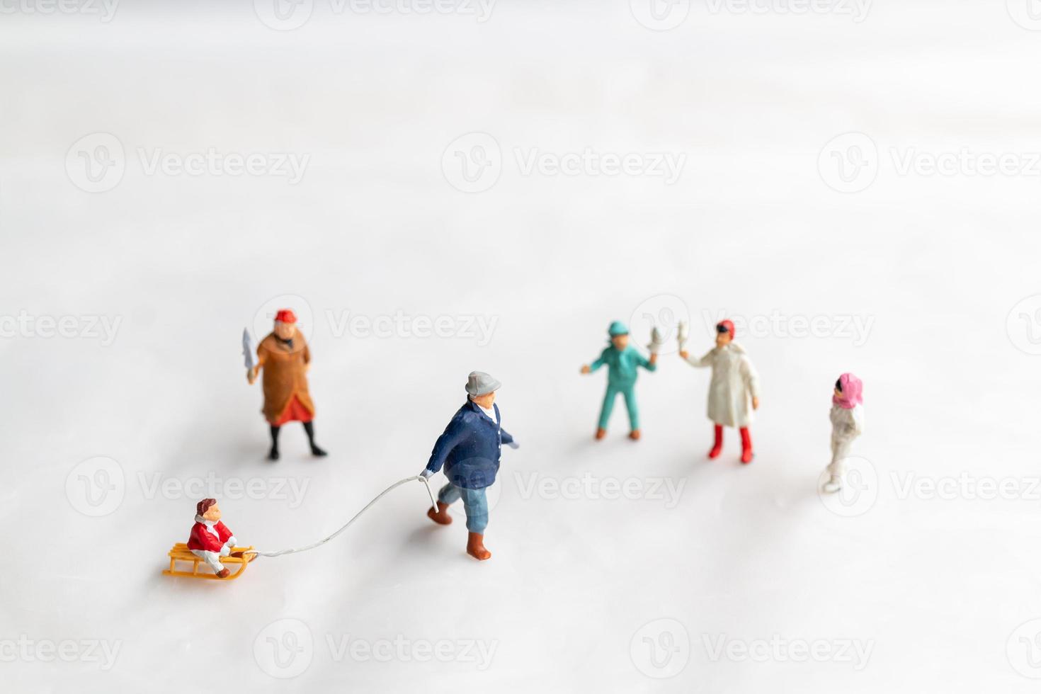 Miniature people Happy family ride a sleigh with snow background photo
