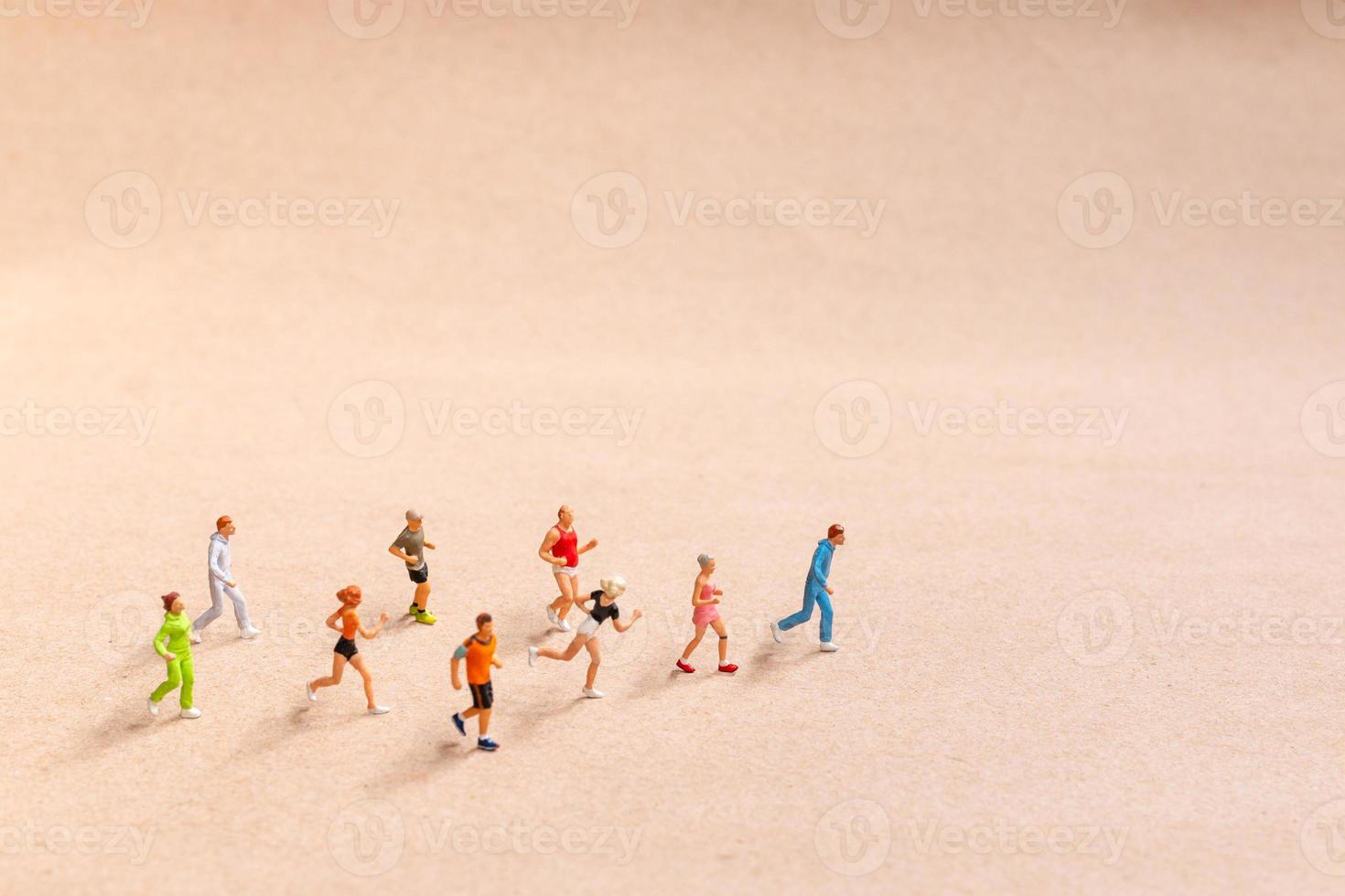 Miniature People exercising while running in a group on the beach photo