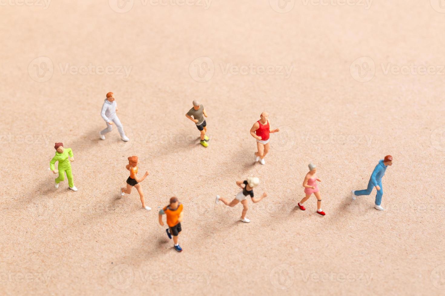 Miniature People exercising while running in a group on the beach photo