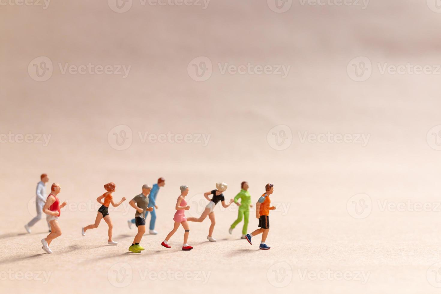 Miniature People exercising while running in a group on the beach photo