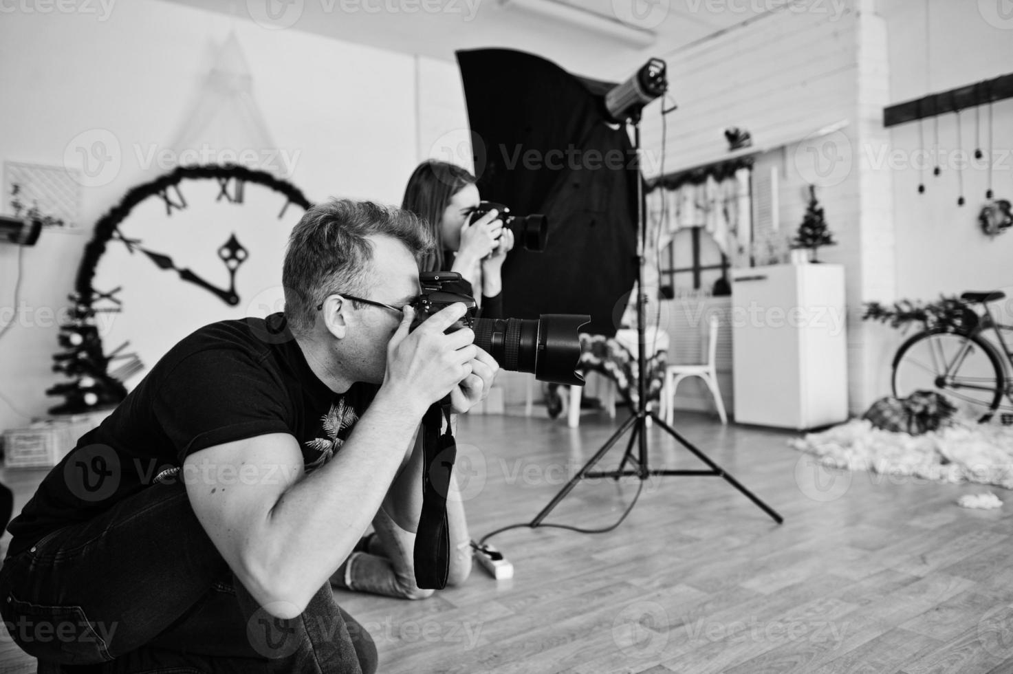 el equipo de dos fotógrafos disparando en el estudio. fotógrafo profesional en el trabajo. foto