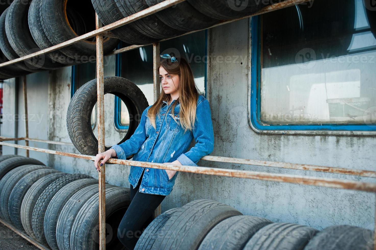 Young hipster girl in jeans jacket and head scarf at tire fitting zone. photo