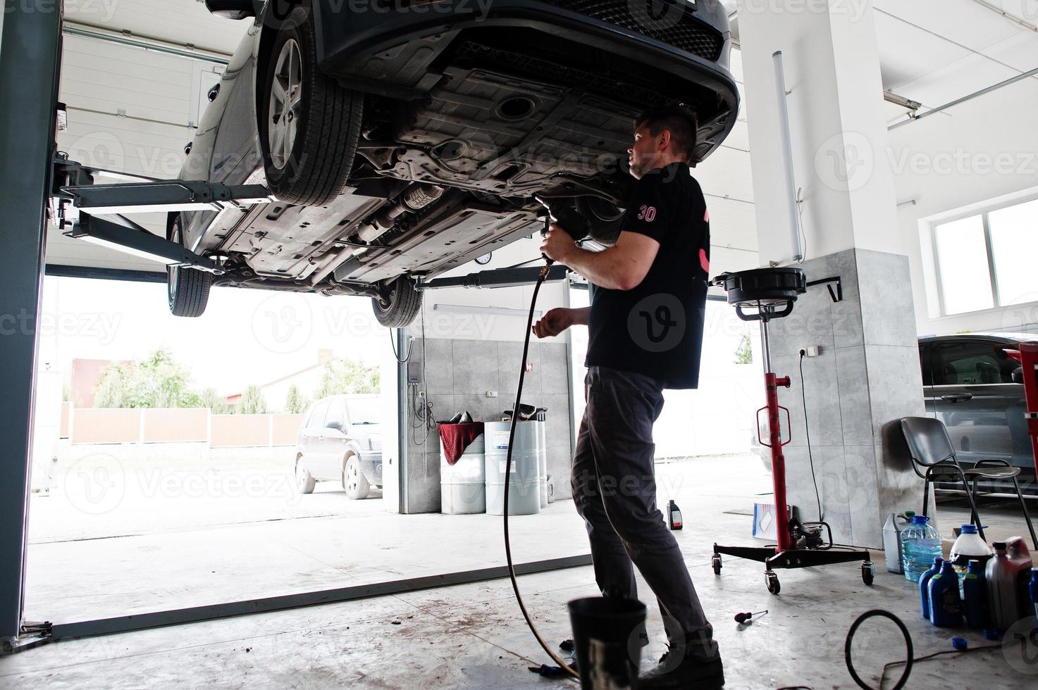 Car repair and maintenance theme. Mechanic in uniform working in auto service. photo