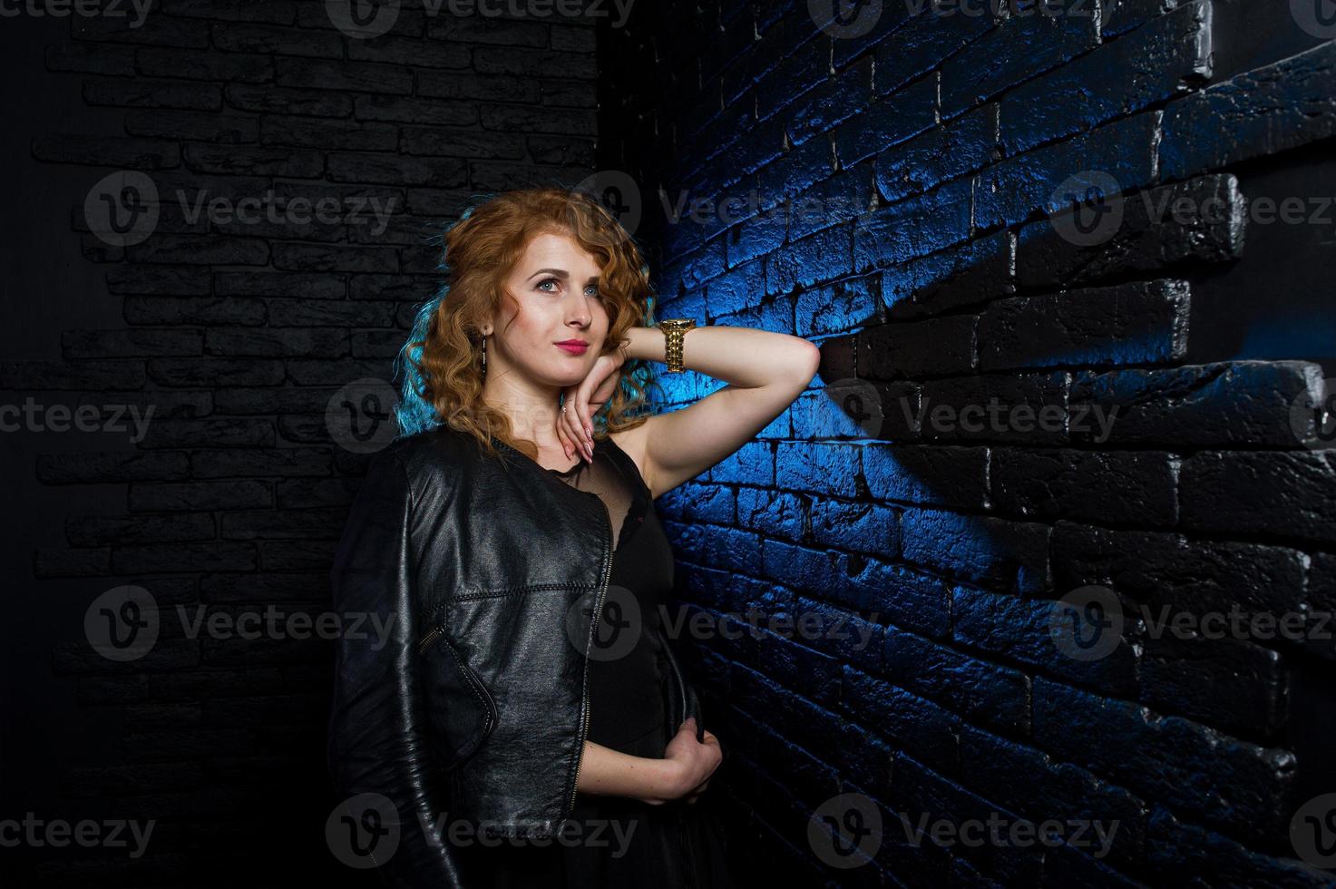chica de rizado en chaqueta de en estudio contra pared de ladrillo negro. 10556042 Foto en Vecteezy