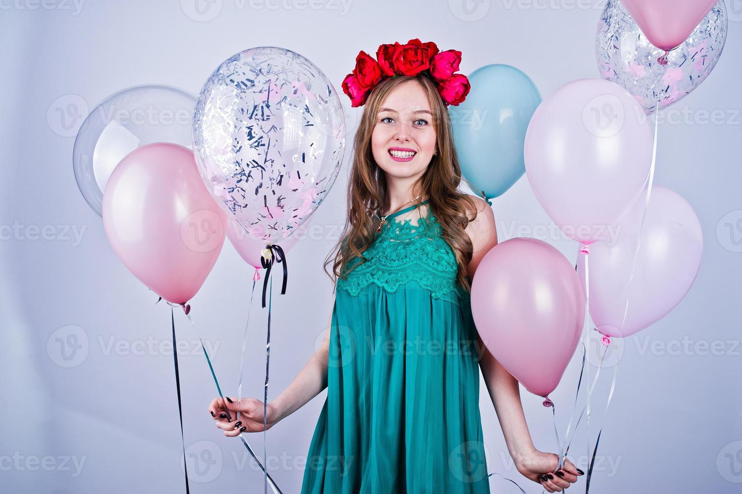 Happy girl in green turqoise dress and wreath with colored balloons isolated on white. Celebrating birthday theme. photo