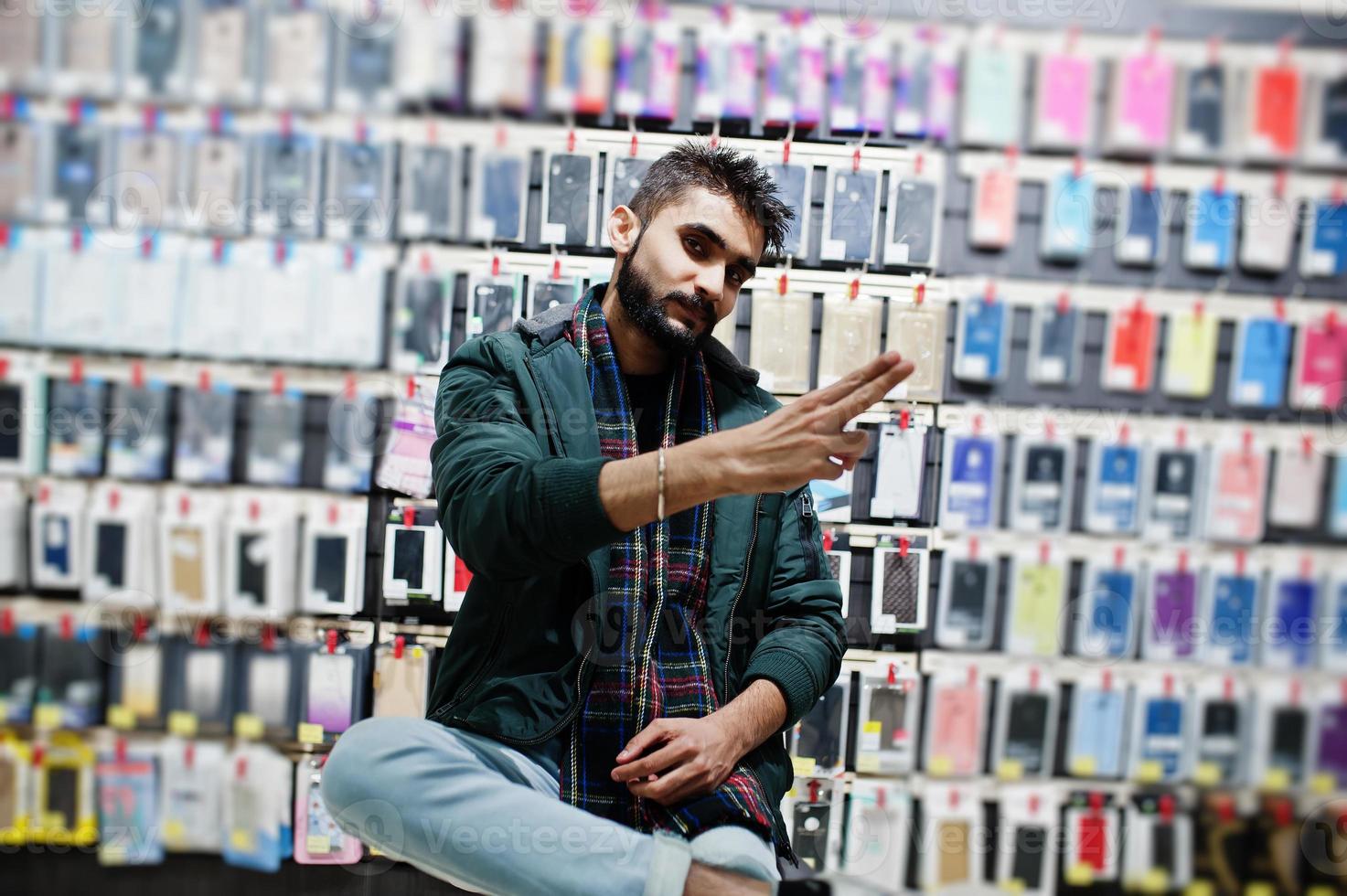 Comprador de cliente de barba india con chaqueta en la tienda de teléfonos móviles. concepto de pueblos y tecnologías del sur de Asia. tienda de celulares foto
